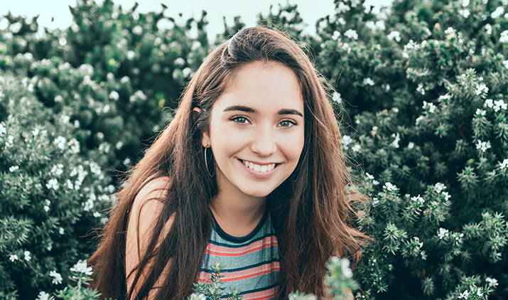 young woman smiling in front of trees