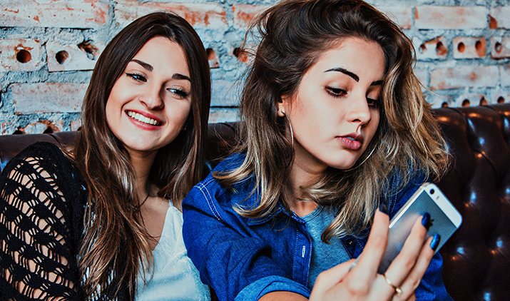 two young woman looking at a phone