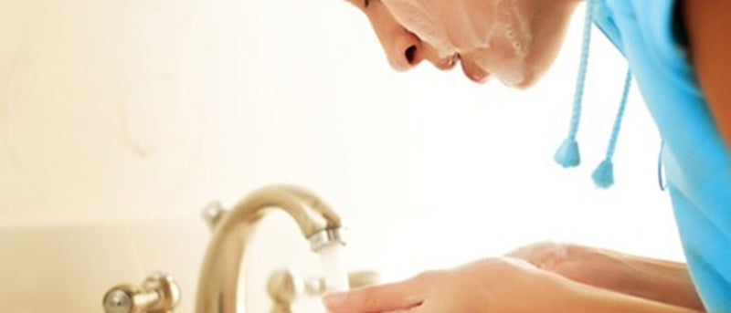 young woman washing her face at the sink