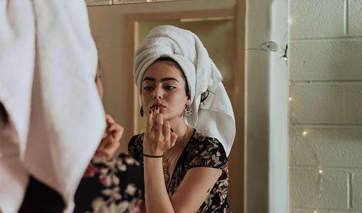 young woman putting product on her face